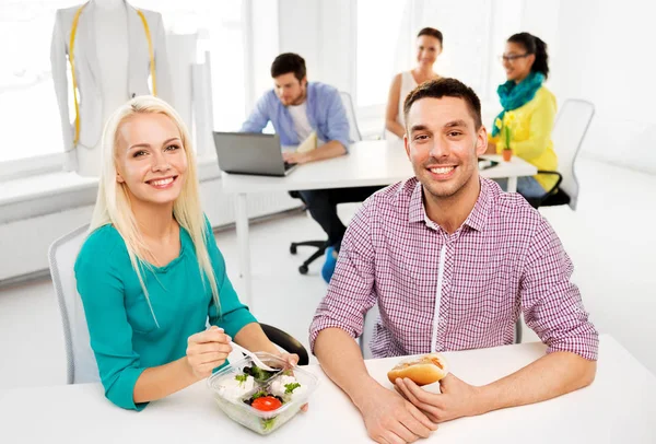 Colegas felizes almoçando e comendo no escritório — Fotografia de Stock