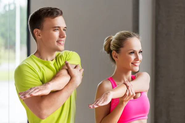 Улыбающиеся мужчина и женщина упражнения в тренажерном зале — стоковое фото