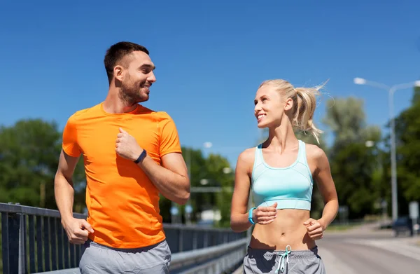 Casal com rastreadores de fitness correndo ao longo da ponte — Fotografia de Stock