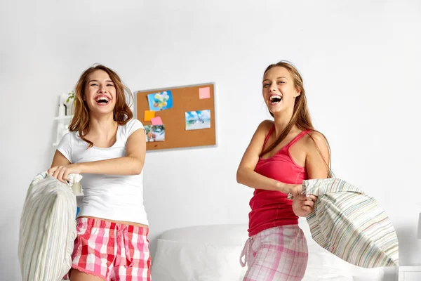 Happy teen girl friends fighting pillows at home — Stock Photo, Image