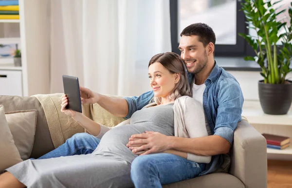 Tablet pc vasıl ev ile hamile kadın ve erkek — Stok fotoğraf