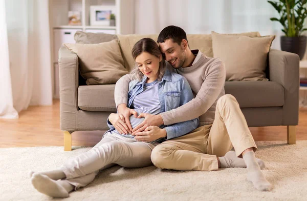 Hombre con mujer embarazada haciendo corazón de la mano en casa — Foto de Stock