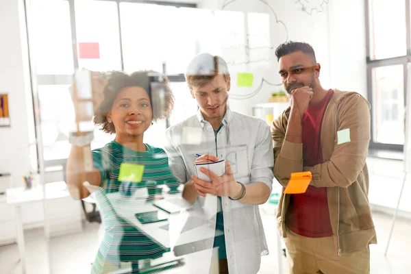 Equipo creativo feliz en el tablero de cristal de la oficina — Foto de Stock