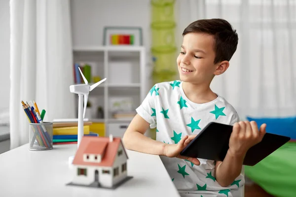 Menino com tablet, casa de brinquedo e turbina eólica — Fotografia de Stock