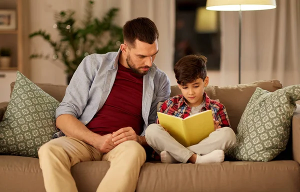 Padre e hijo leyendo libro sofá en casa —  Fotos de Stock