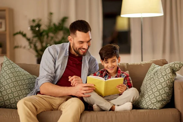 Lycklig far och son läser bok soffa hemma — Stockfoto