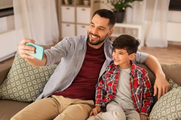 Pai e filho tomando selfie em casa — Fotografia de Stock