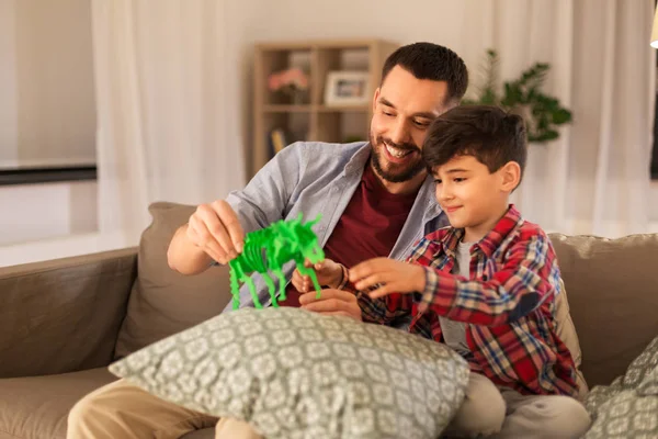 Far och son leker med leksaksdinosaurie hemma — Stockfoto