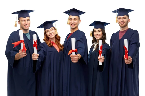 Graduates in mortar boards with diplomas — Stock Photo, Image