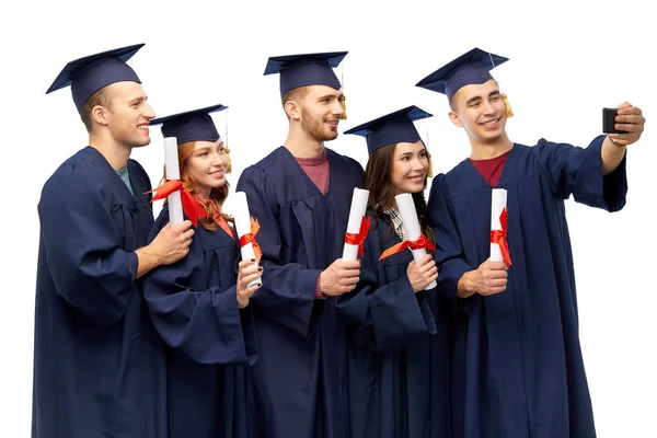 Diplomados com diplomas tirando selfie por celular — Fotografia de Stock