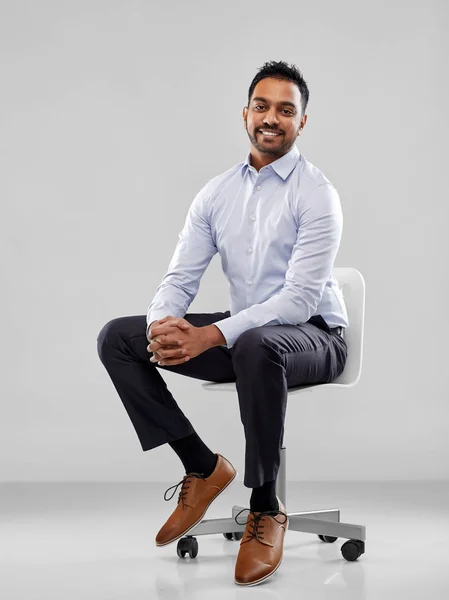 Homme d'affaires indien souriant assis sur une chaise de bureau — Photo