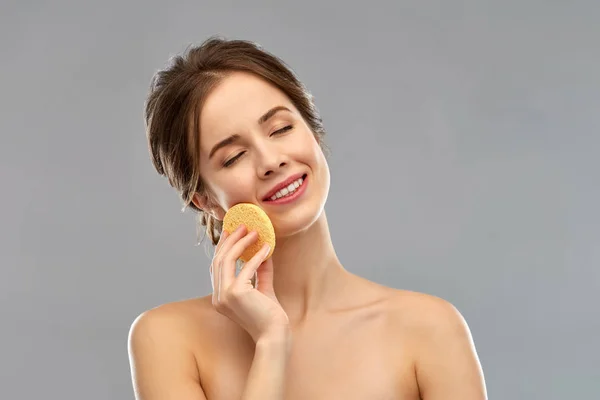 Young woman cleaning face with exfoliating sponge — Stock Photo, Image