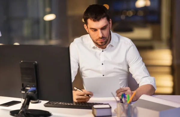 Homme d'affaires avec des papiers travaillant au bureau de nuit — Photo