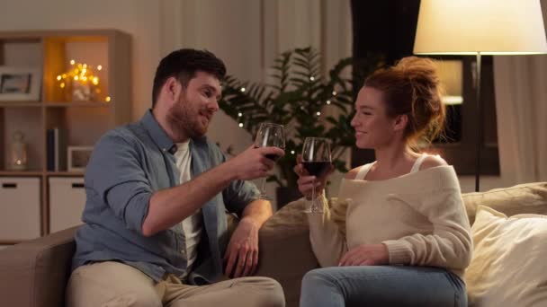 Ευτυχισμένο ζευγάρι πόσιμο κόκκινο κρασί στο σπίτι το βράδυ — Αρχείο Βίντεο