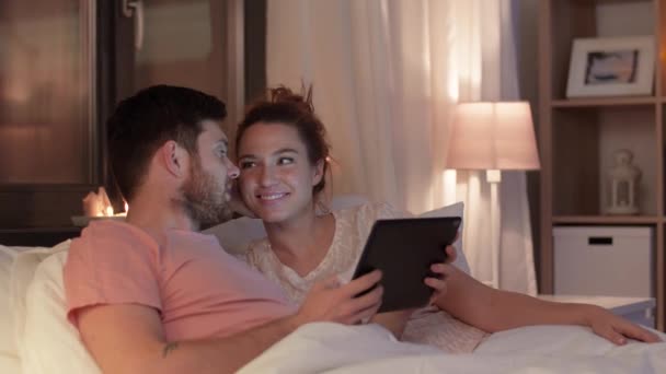 Casal feliz usando computador tablet na cama à noite — Vídeo de Stock