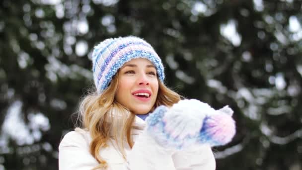 Šťastná mladá žena fouká do sněhu v zimě lese — Stock video