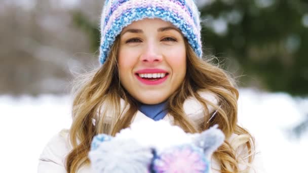 Щаслива молода жінка дме до снігу в зимовому лісі — стокове відео