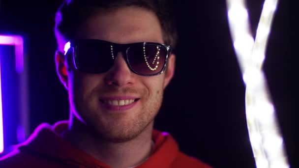 Mann mit Sonnenbrille blinzelt über Neonlichter — Stockvideo