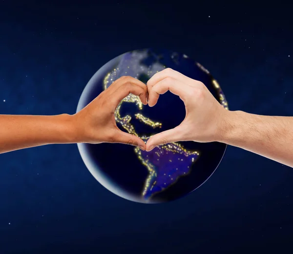 Hands showing heart gesture over earth in space — Stock Photo, Image