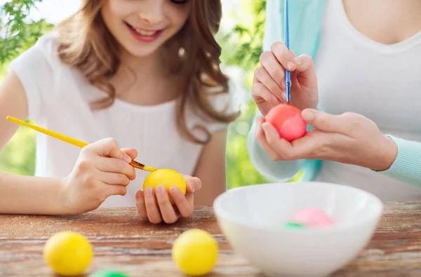 Glücklich lächelnde Mädchen und Mutter beim Färben von Ostereiern — Stockfoto