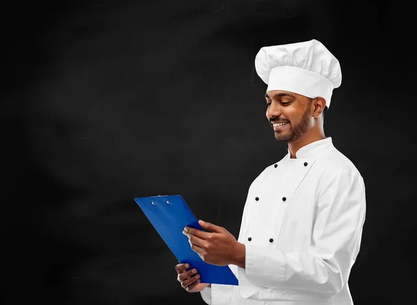 Szef kuchni, czytanie menu schowka nad tablica — Zdjęcie stockowe