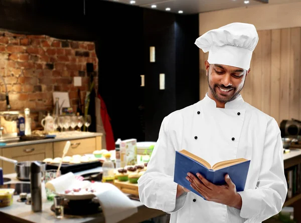 Chef indio hombre feliz leyendo libro de cocina en la cocina —  Fotos de Stock