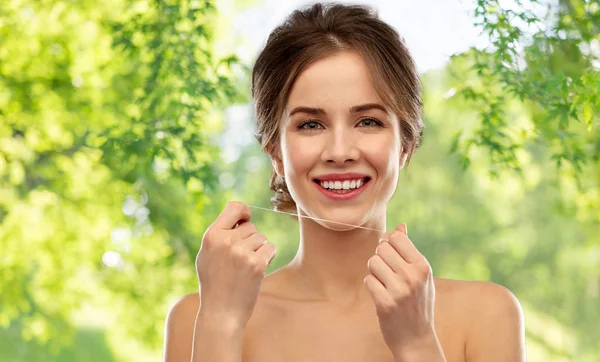 Happy young woman with dental floss cleaning teeth — Stock Photo, Image