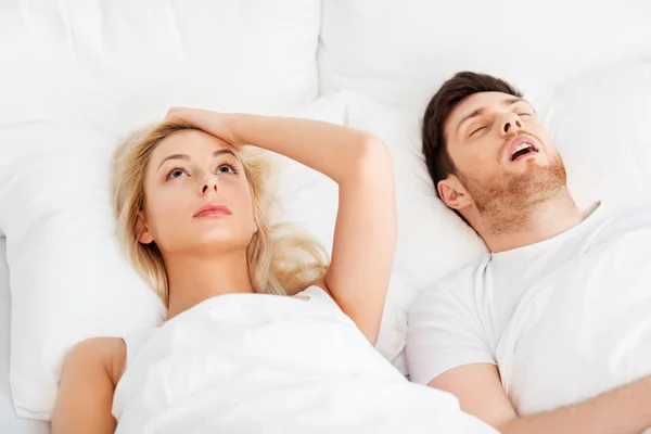 Unhappy woman in bed with snoring sleeping man — Stock Photo, Image