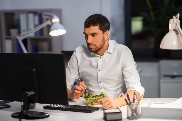 Hombre de negocios con computadora comiendo en la oficina nocturna — Foto de Stock