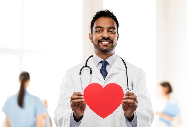 Lächelnder indischer Arzt mit roter Herzform — Stockfoto