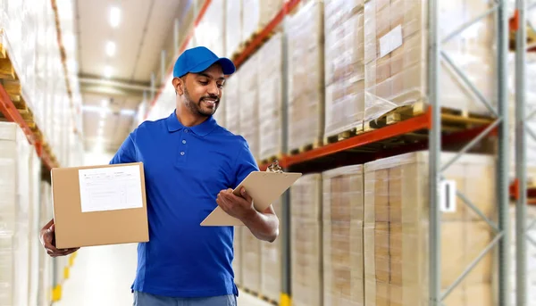 Delivery man with box and clipboard at warehouse — Stock Photo, Image