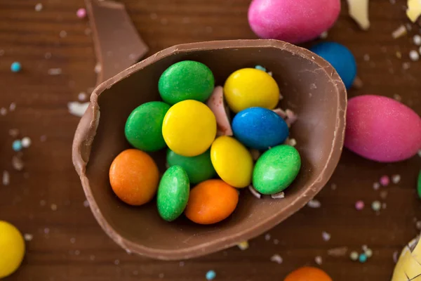 Chocolate egg and candy drops on wooden table — Stock Photo, Image