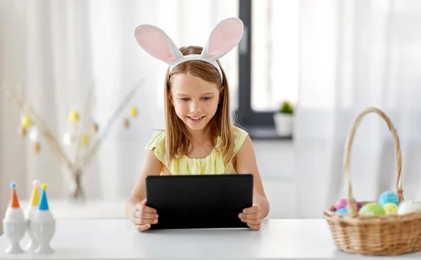 Menina feliz com tablet pc e ovos de Páscoa em casa — Fotografia de Stock