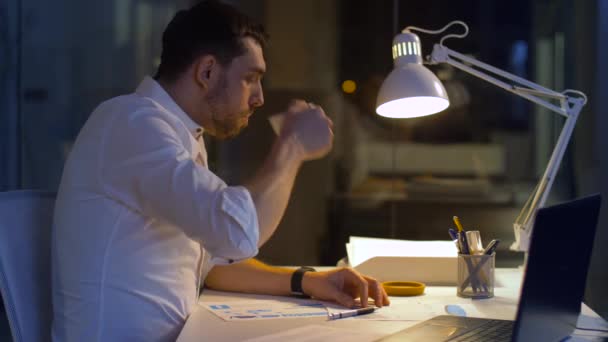 Zakenman met bestanden en laptop werken bij nacht — Stockvideo