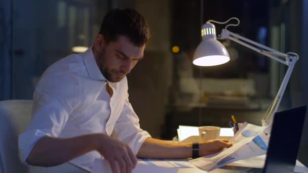 Бизнесмен с файлами и ноутбуком, работающий по ночам — стоковое видео