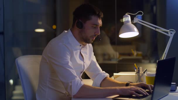 Zakenman in hoofdtelefoon met laptop op het kantoor van de nacht — Stockvideo