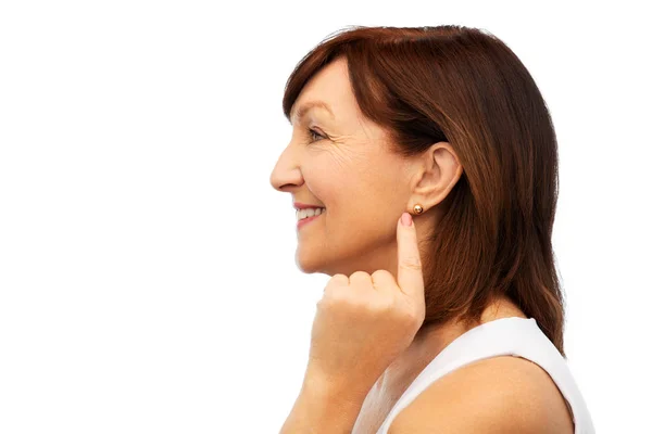 Souriant femme âgée pointant vers sa boucle d'oreille — Photo