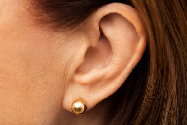 Крупним планом старше жіноче вухо з золотими сережками — стокове фото