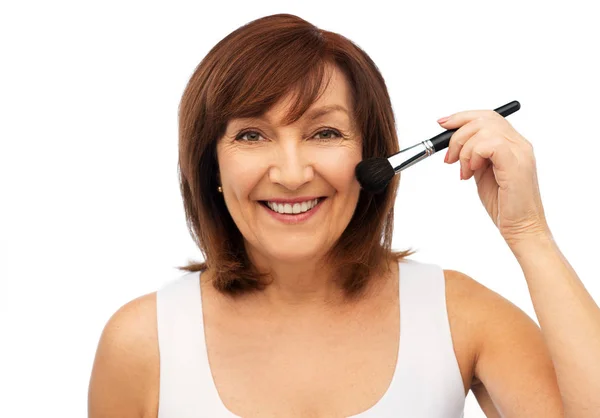 Femme âgée souriante avec brosse à blush maquillage — Photo