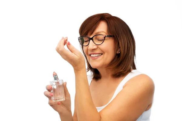 Mujer mayor oliendo perfume de su muñeca — Foto de Stock