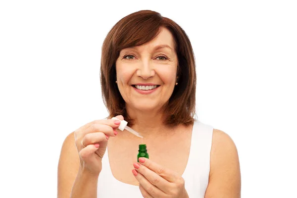 Smiling senior woman with bottle of serum — Stock Photo, Image