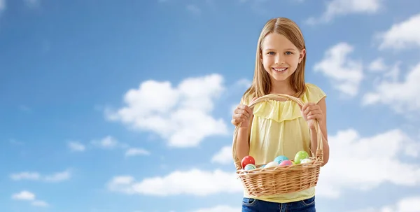 Happy girl with colored eggs in wicker basket — Stock Photo, Image