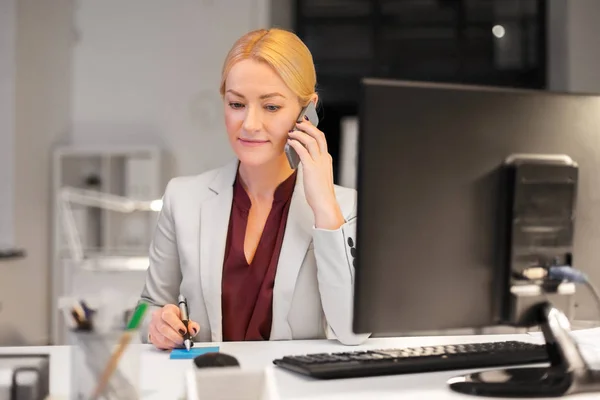 Business woman calling on sartphone at night office — стоковое фото