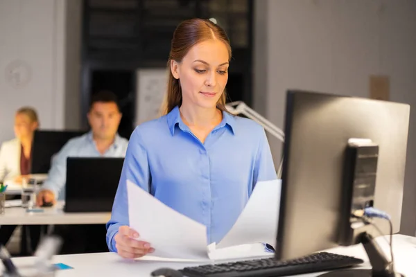 Affärskvinna med papper som arbetar på natten kontor — Stockfoto