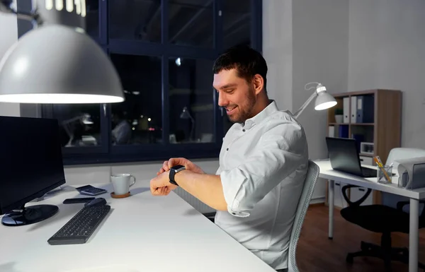 Happy businessman using smart watch at nigh office — Stock Photo, Image