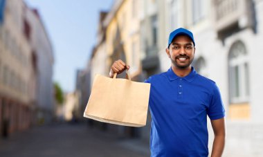 indian delivery man with food in paper bag in city clipart