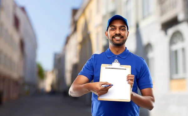 Happy indian delivery man with clipboard in city — Stock Photo, Image