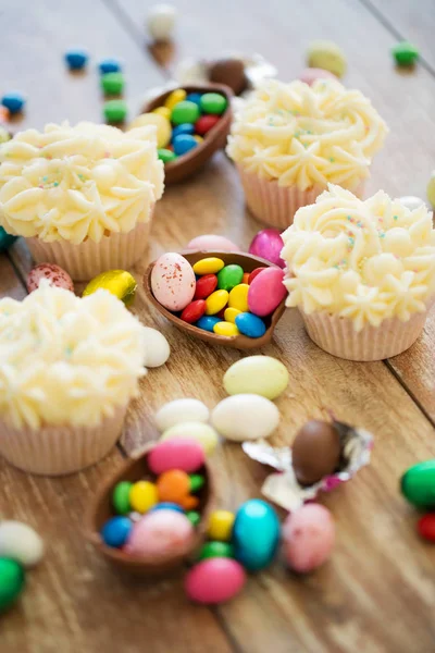 Cupcakes with chocolate eggs and candies on table — Stock Photo, Image