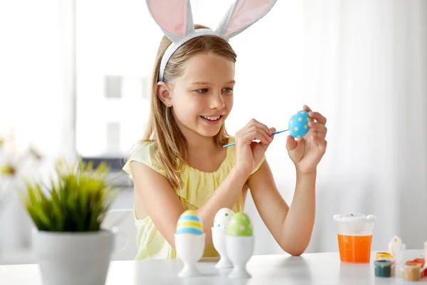 Happy girl coloring easter eggs at home — Stock Photo, Image