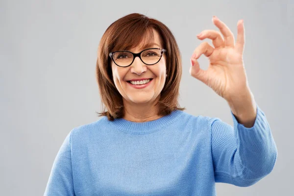 Счастливая пожилая женщина в очках, показывающих знак ладони — стоковое фото